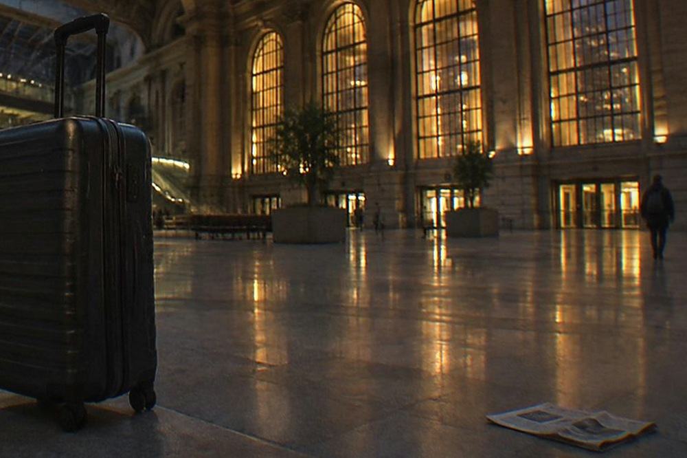 Empty train hall concourse at night with tall arched windows and low lighting