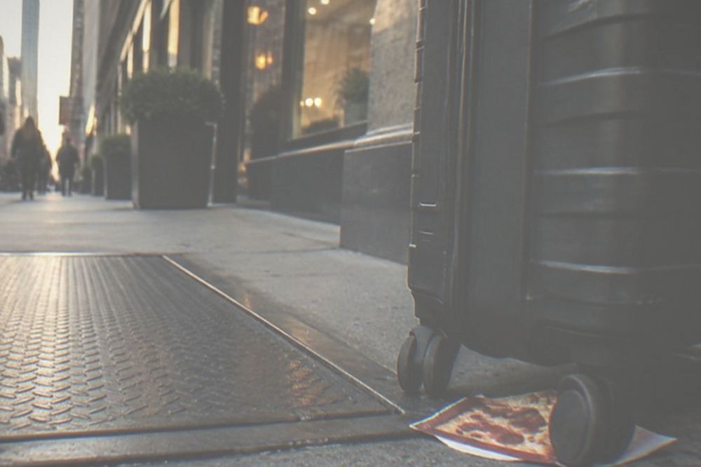Rolling suitcase waiting beside a Midtown storefront in evening light