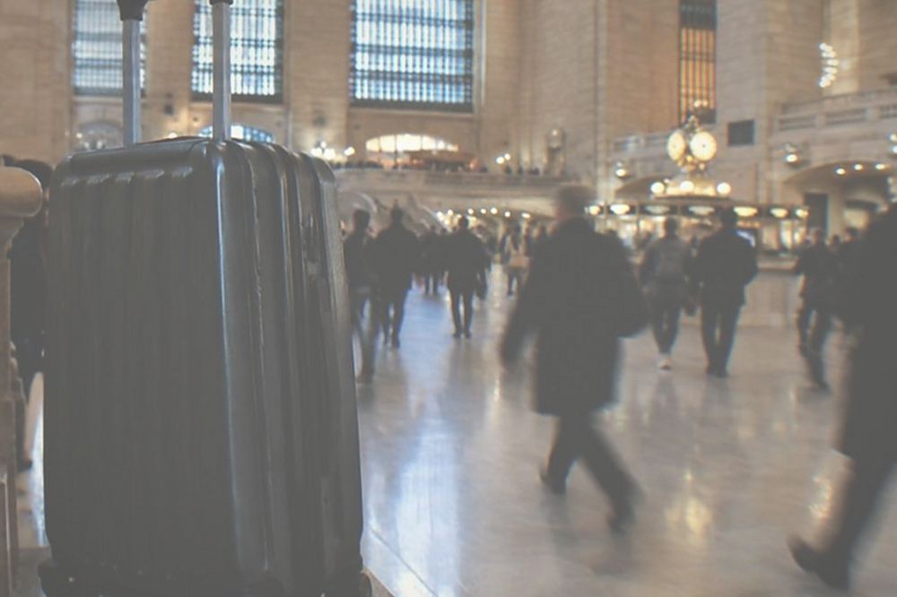 Commuters walking through a wide station concourse with a departures board overhead