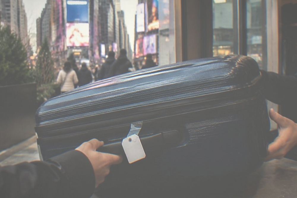 A staffed bag storage counter with a suitcase being handed over across a counter