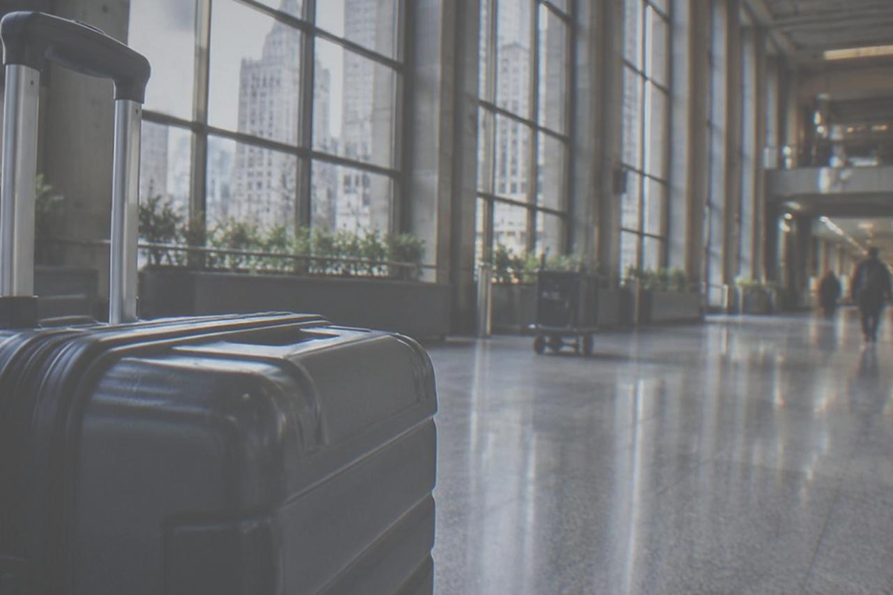 Airport terminal corridor with tall windows and a moving walkway, empty of travellers