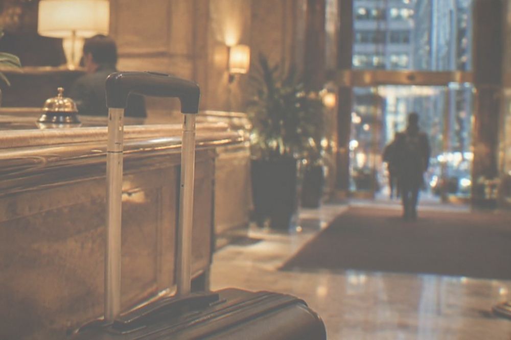 A suitcase waiting beside a hotel bell desk counter in a warmly lit lobby