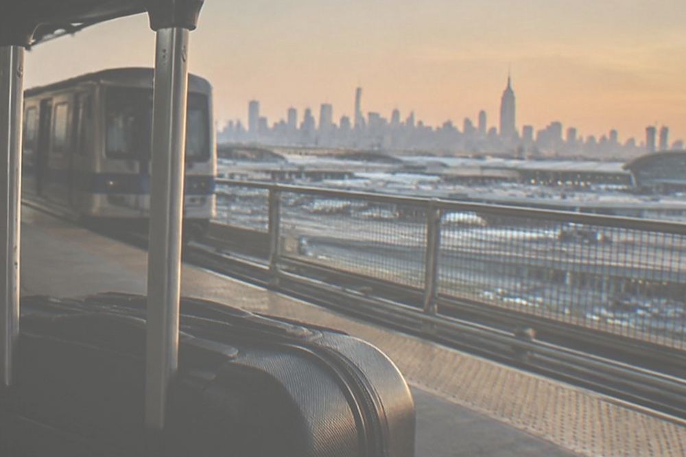 An elevated airport train platform with a stationary train and a view of terminal buildings