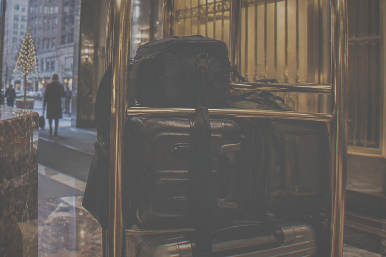 Hotel front desk with a bell cart of suitcases parked beside the counter in a marble lobby