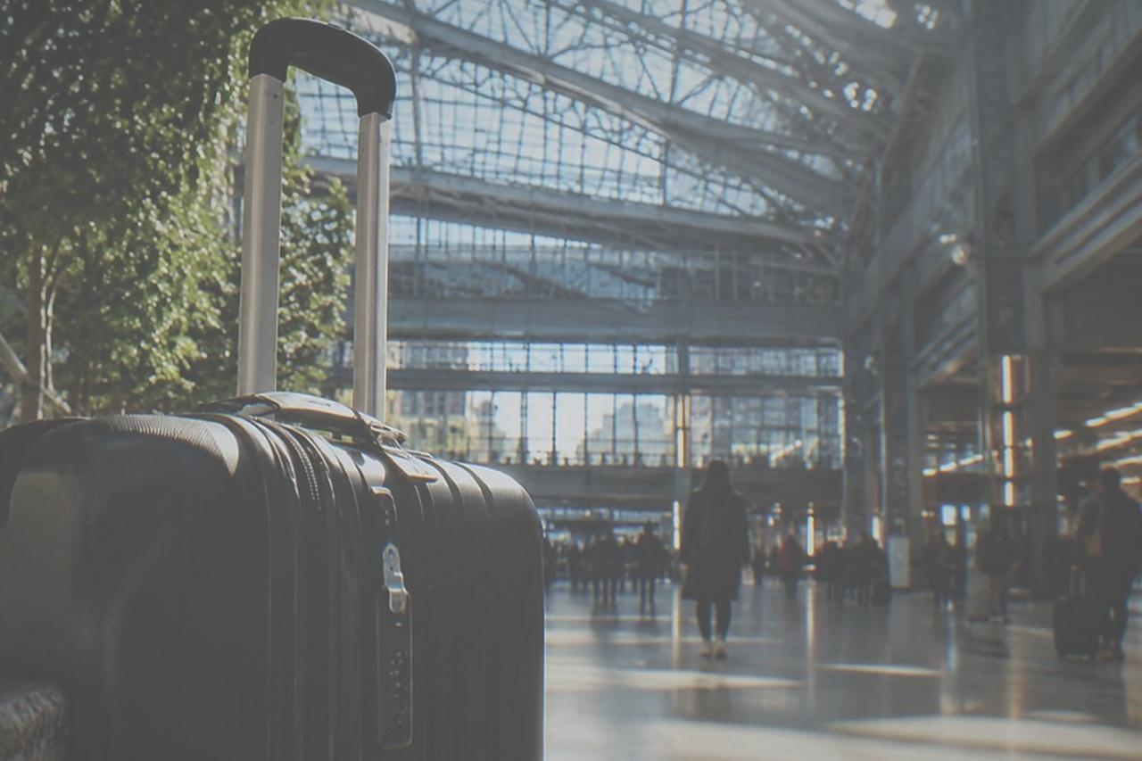 The tall glass atrium of Moynihan Train Hall with sunlight falling on the floor and a departure board overhead