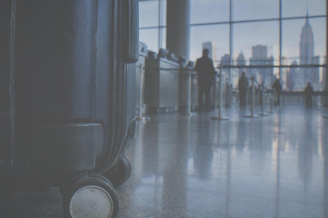 Empty departure hall at John F. Kennedy International Airport with tall windows and airline counters in soft morning light