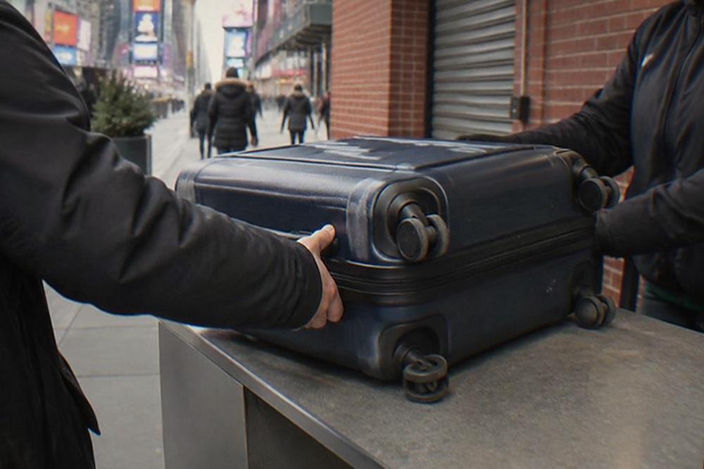 A staffed bag storage counter with a suitcase being handed over across the counter