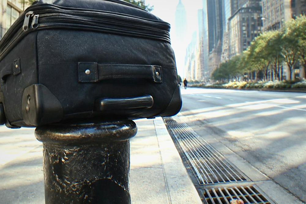 A long Manhattan avenue in morning light with wide sidewalks and a distant skyline
