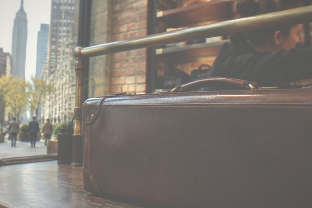 A shop counter with a staffed reception desk where a traveller hands over a suitcase