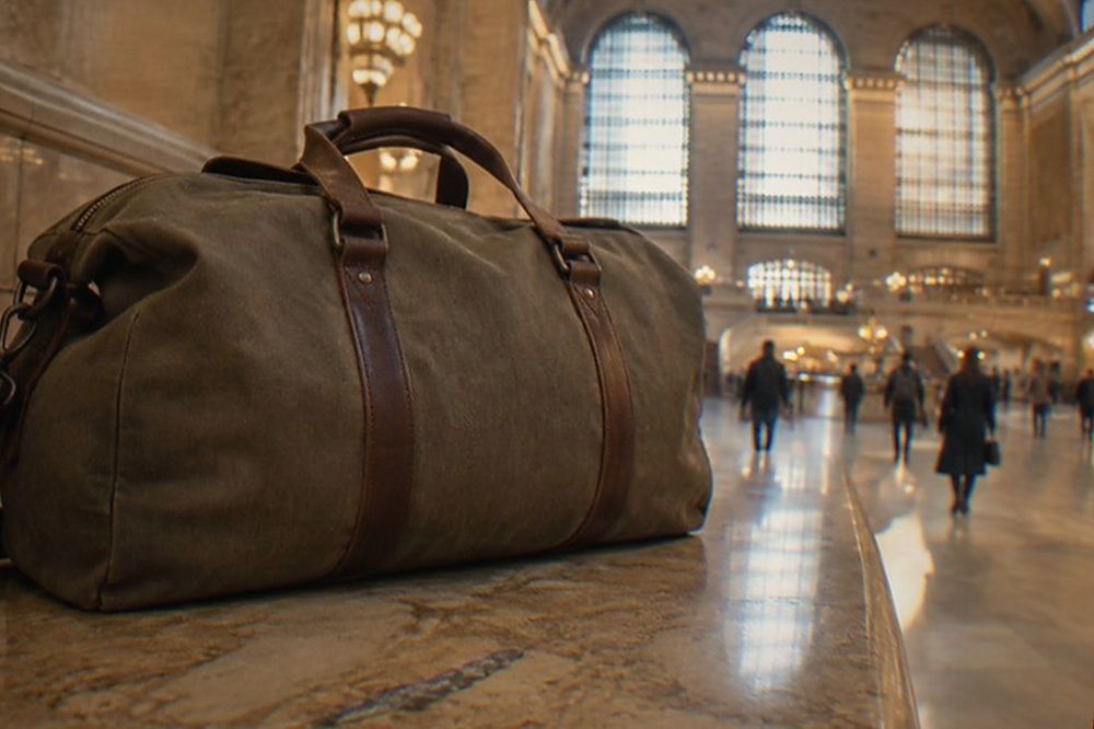 Wide marble corridor of a grand railway terminal with arched windows and a few travellers walking