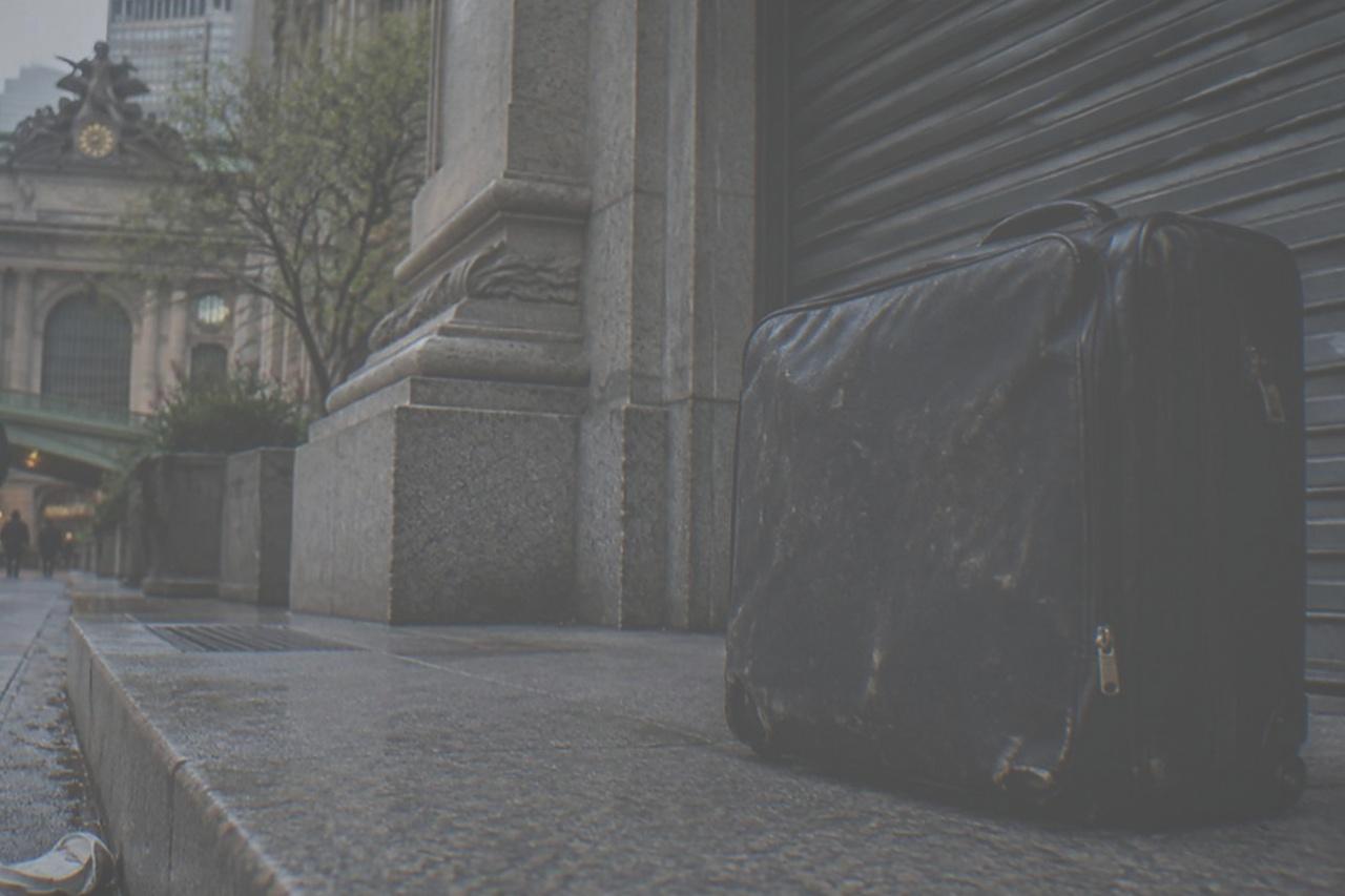 Empty sidewalk outside a stone railway terminal in Manhattan with a closed storefront beside it