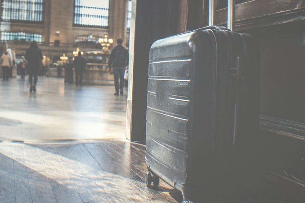 A suitcase waiting beside an open doorway with daylight on a wood floor