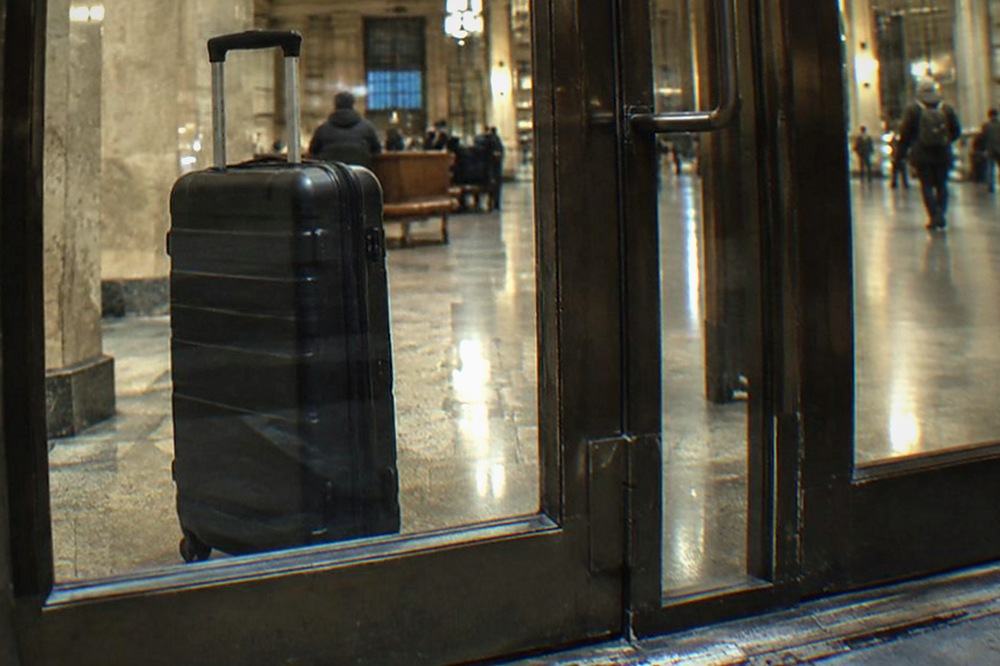 A train hall entrance at night with glass doors and a quiet concourse lit from above