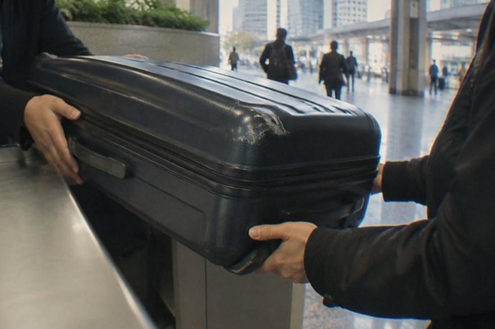 A staffed storage counter with a large hard-sided suitcase being handed over