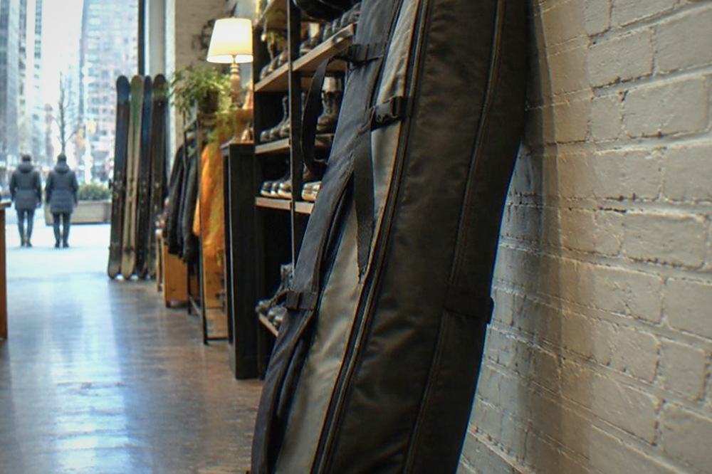 A long ski bag leaning against a wall inside a storage shop
