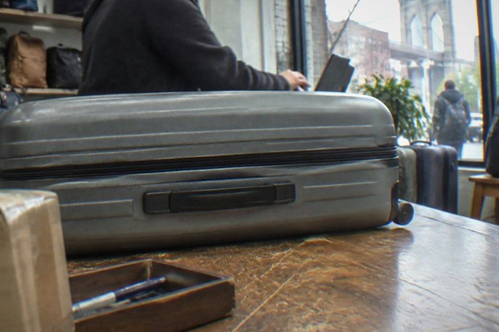 A shop counter with a suitcase parked beside it and a staff member behind the register
