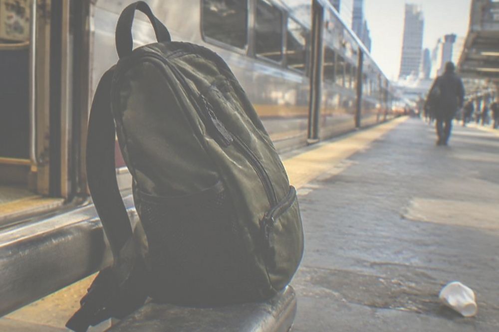 A regional train at a platform with doors open and a small day pack on a seat