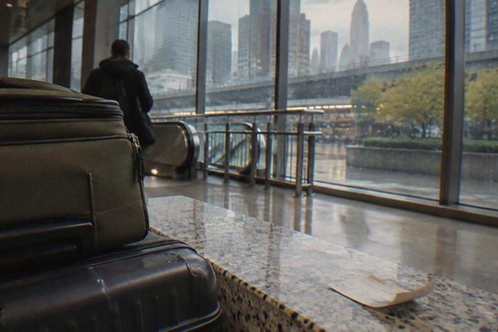 A traveler pulling two suitcases across an airport terminal concourse toward a rail station entrance