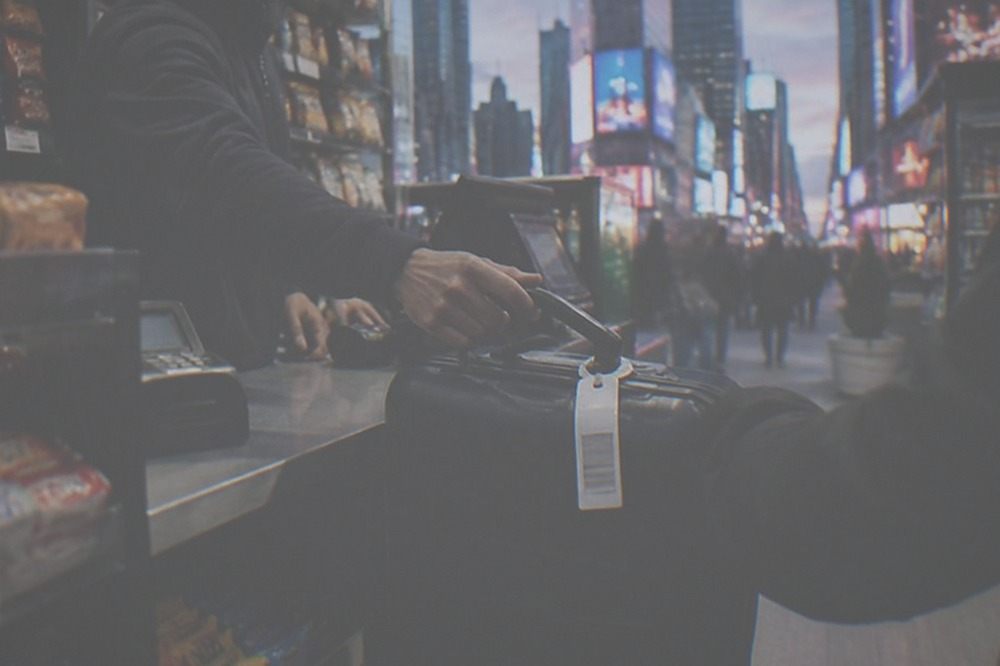 A staffed shop counter where a suitcase is being checked in behind a small reception desk