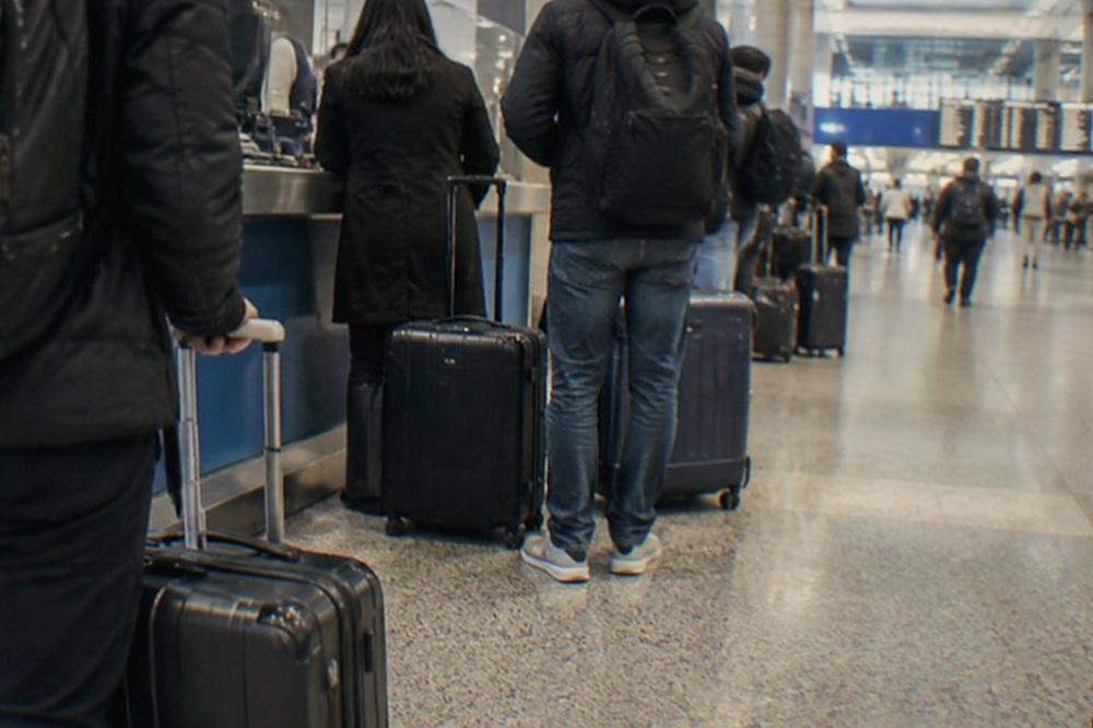 Long-distance train station concourse with a staffed service counter and a queue of rolling suitcases