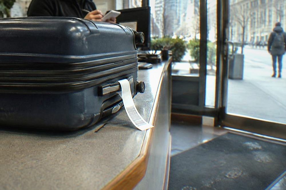 Shop counter with a tagged suitcase and a staff member writing a storage receipt