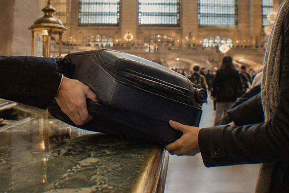 A shop counter with a suitcase being handed over to a staff member behind the desk