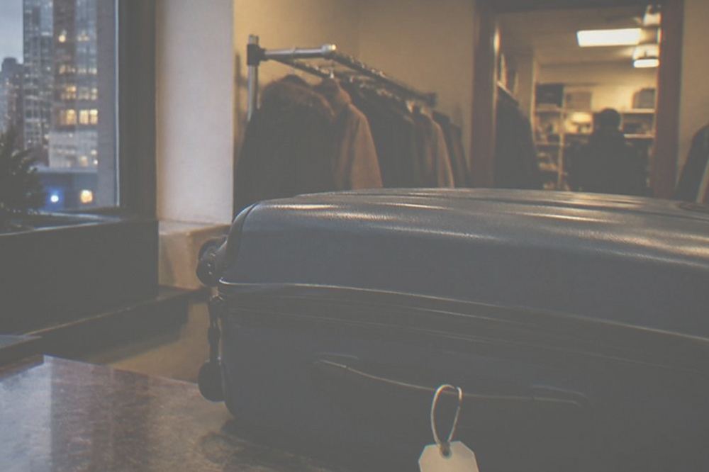 A staffed shop counter with a tagged suitcase placed behind it in a back room