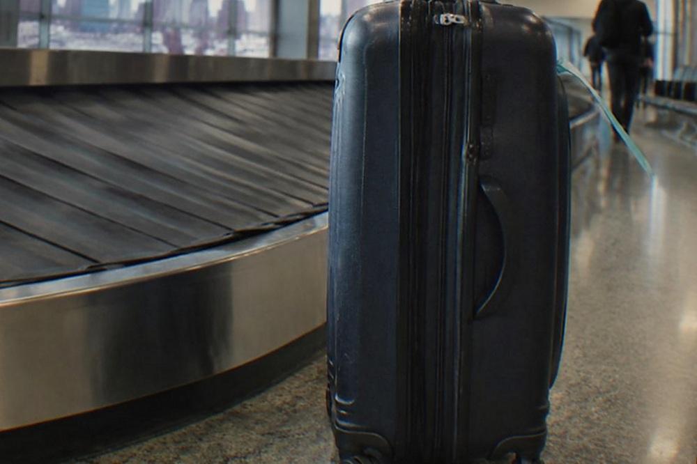 Airline baggage claim carousel inside a LaGuardia terminal with a few suitcases on the belt