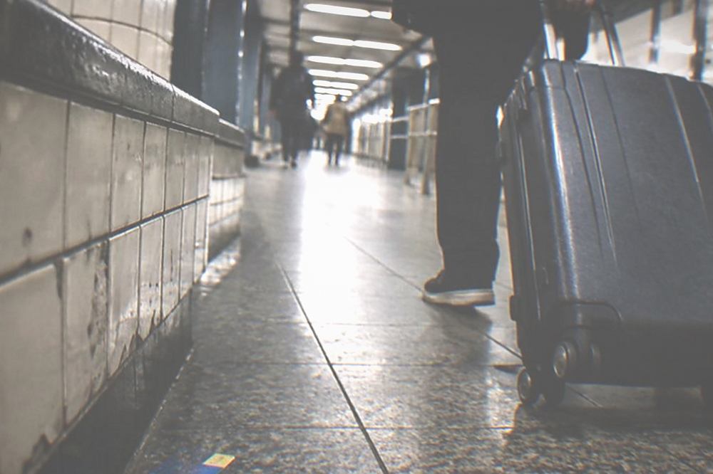 A traveller pulling a wheeled suitcase through a New York subway station corridor