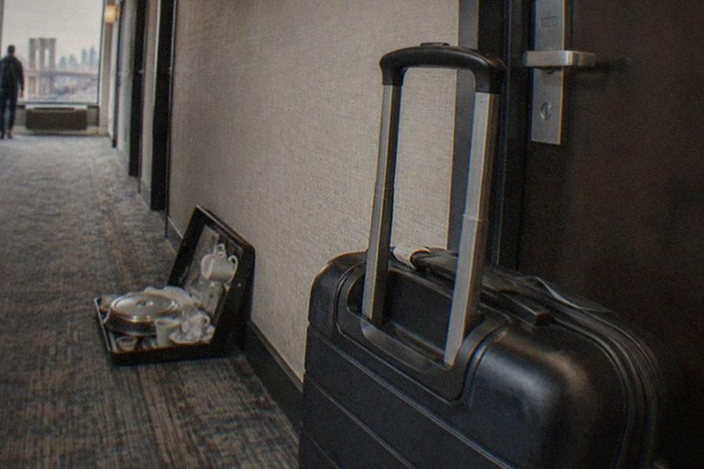 Hotel room door with a checkout time sign and a suitcase waiting in the hallway