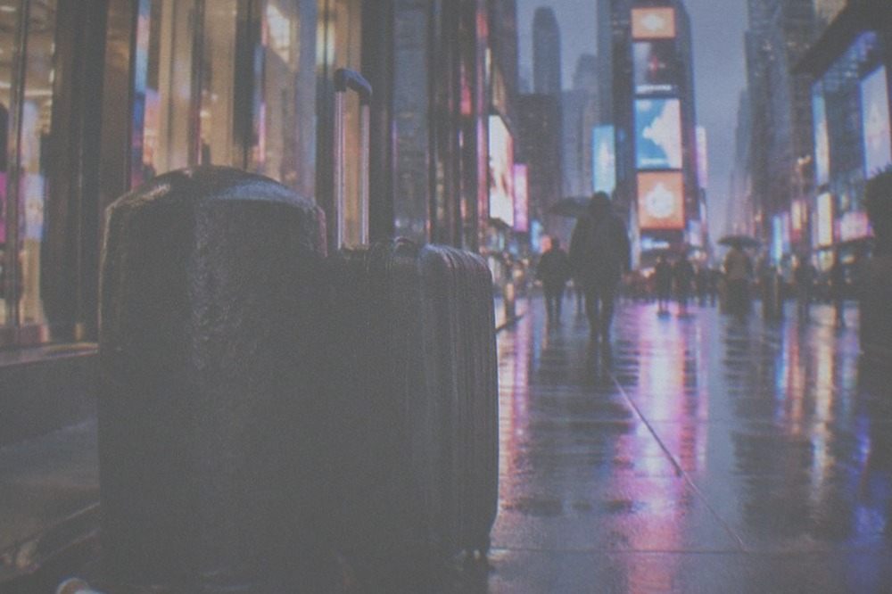 Evening street in Manhattan with a suitcase waiting outside a lit storefront