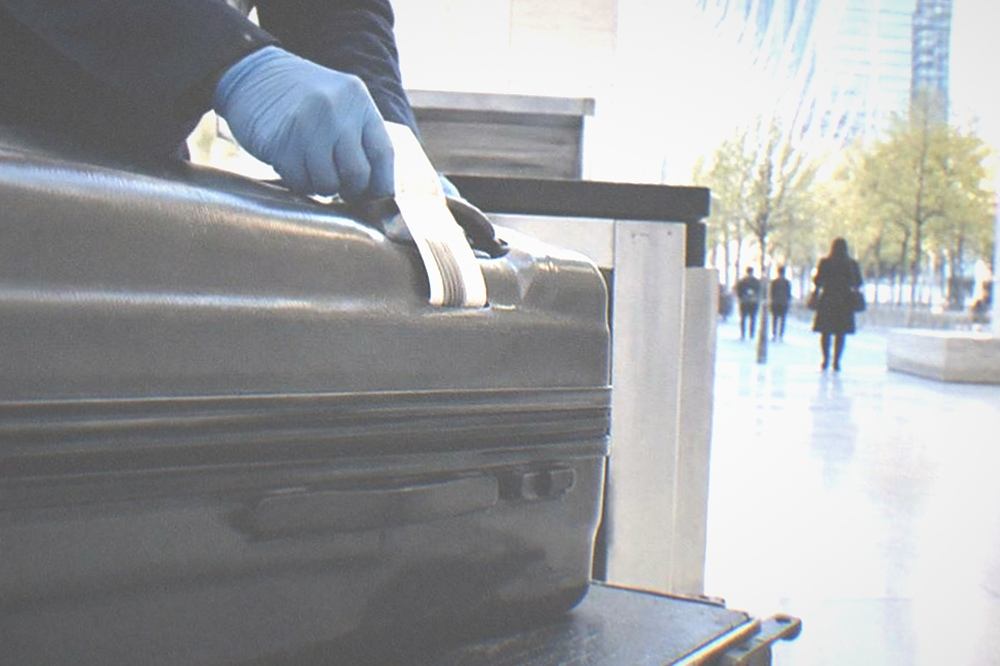 Traveller handing a suitcase across a hotel storage counter while staff attach a tag