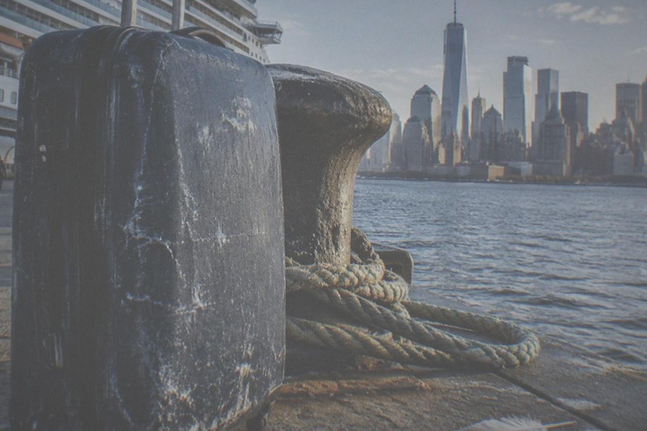 Cruise ship docked at a Manhattan pier with the city skyline behind it on a clear morning