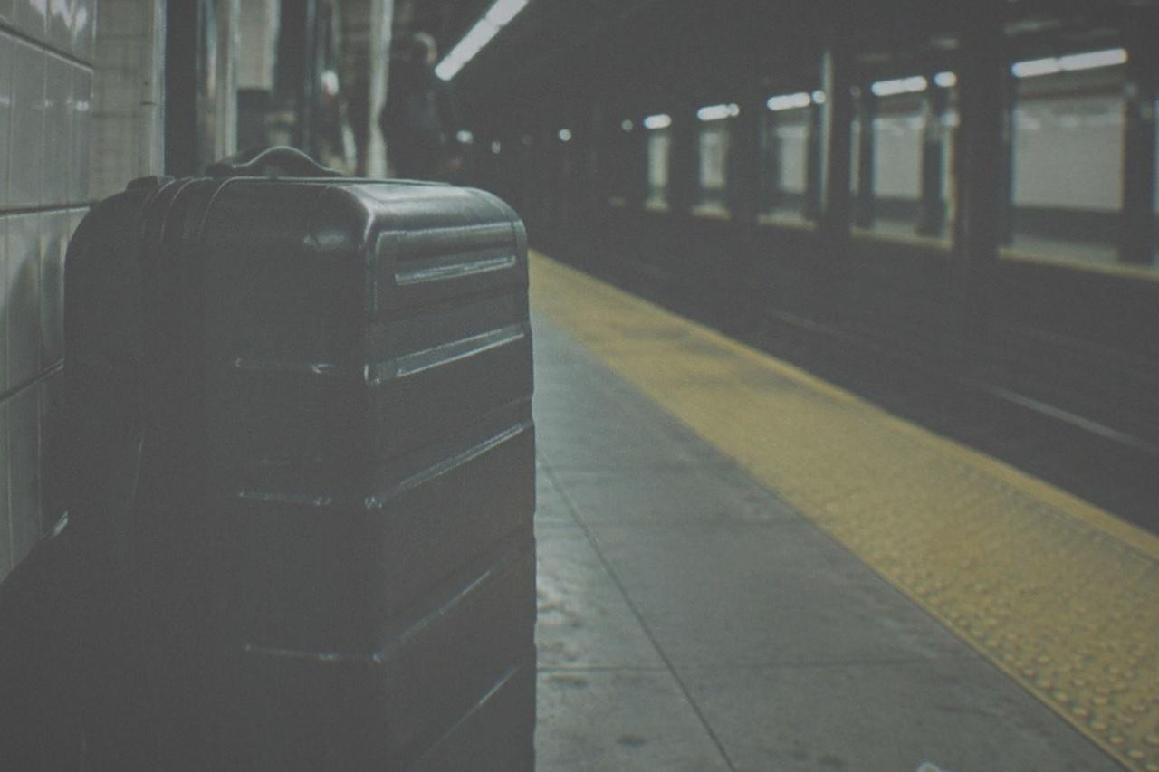 An empty New York subway platform with a tiled wall and a bench along the track