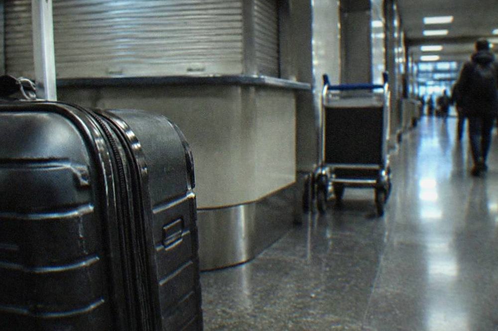 Dimly lit airport corridor with a baggage storage counter sign above a closed desk
