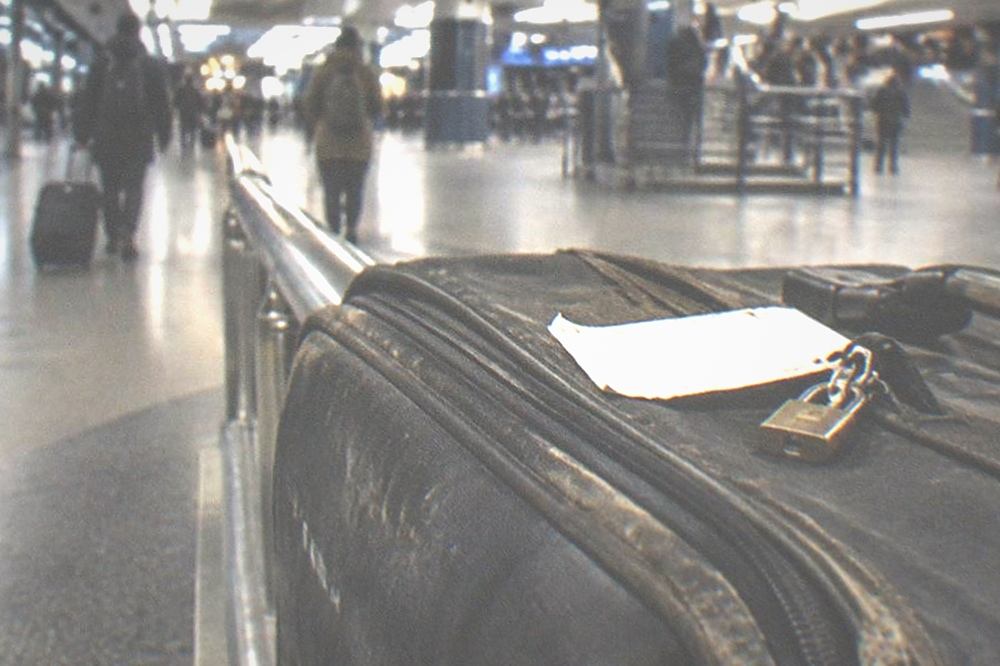 A receipt and a small padlock resting on a suitcase at a counter