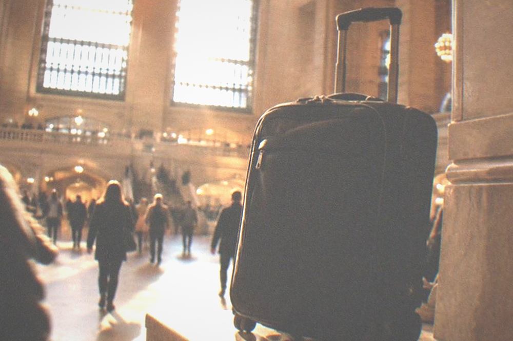 Traveller pulling a wheeled suitcase across a wide station concourse