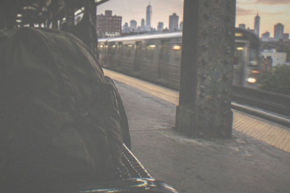 Subway platform with a train arriving beside a rider with a backpack
